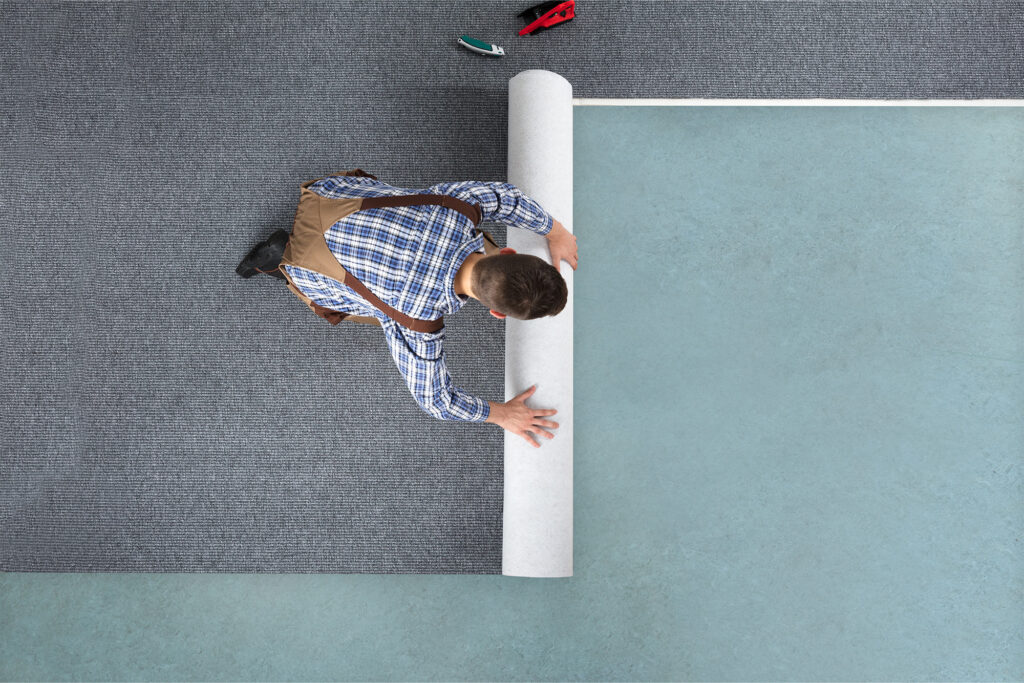Man rolling out carpet for installation | Carpetland USA Granite & Flooring